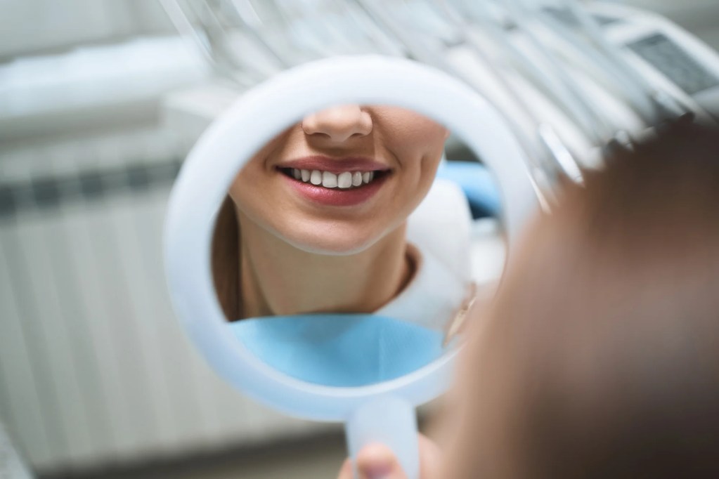 Dental Patient Smiling With Tooth Veneer in Mirror