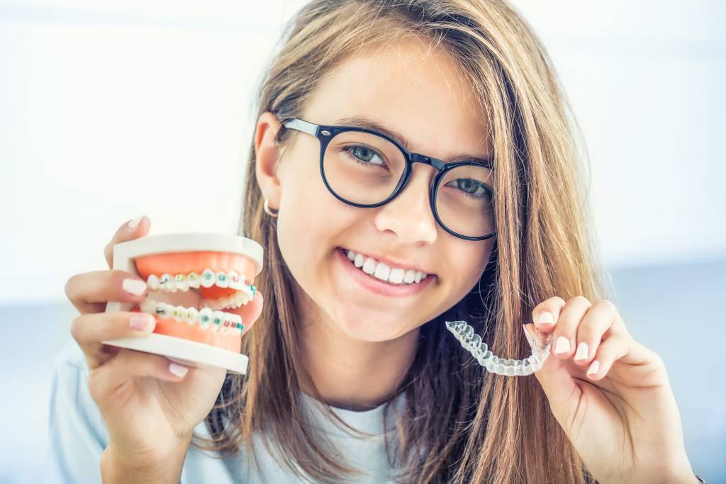 woman displaying difference between traditional braces and Invisalign