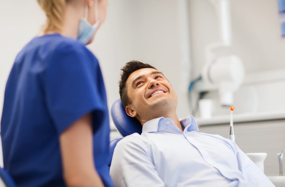 female dentist with happy male patient at clinic